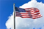 American Flag high on pole - blue sky and cloud background